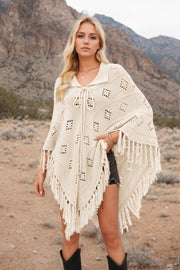 Cream knit poncho with geometric pattern and fringe, tie neck, open front, acrylic.