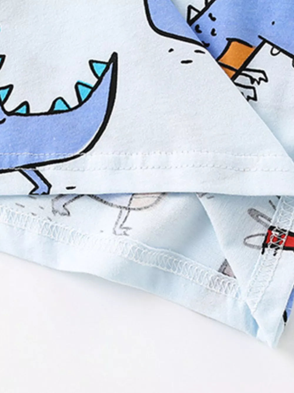 Light blue cotton toddler t-shirt with playful cartoon dinosaur print and contrast stitching.