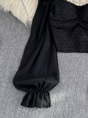 Black Swiss dot maternity blouse with ruffled sleeve cuff and ruched bodice detail.