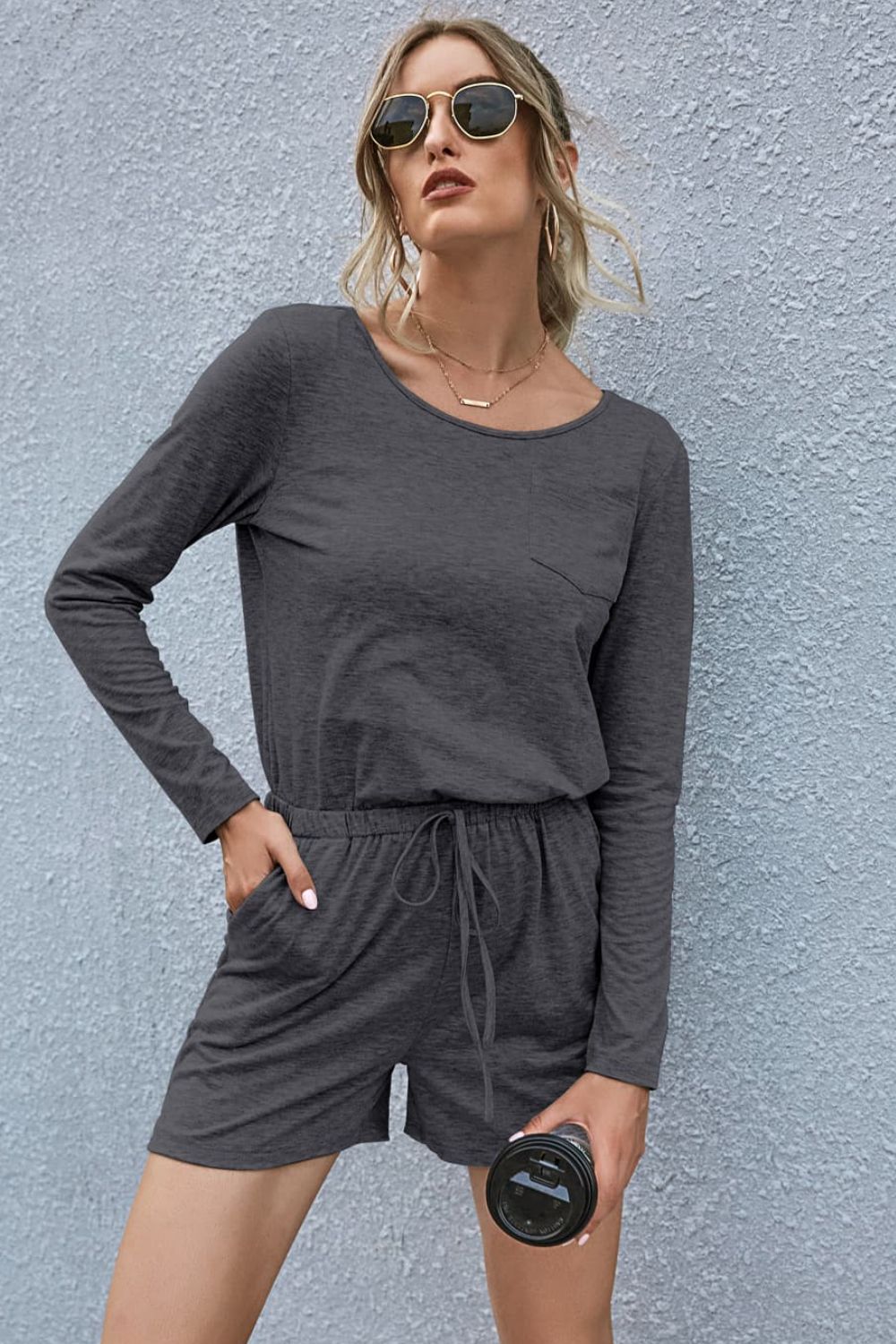 Dark gray jersey pocket romper with long sleeves, drawstring waist, and shorts.