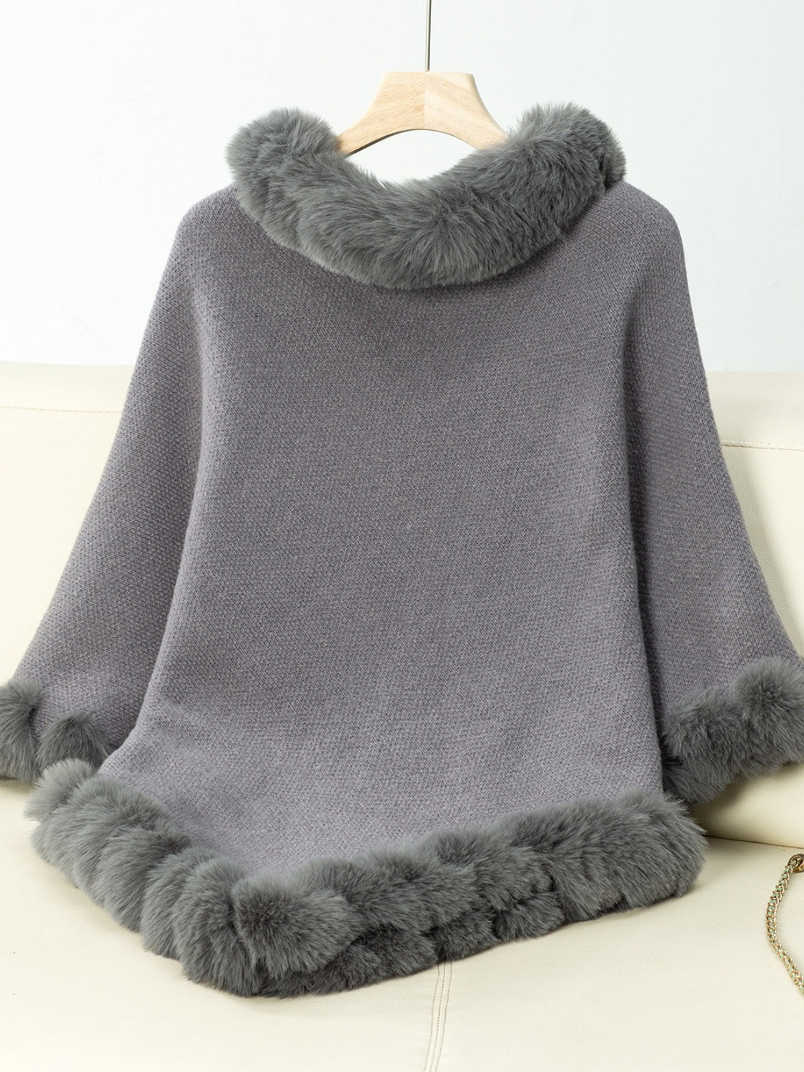 Dark gray knit poncho with faux fur trim at neckline and hem.
