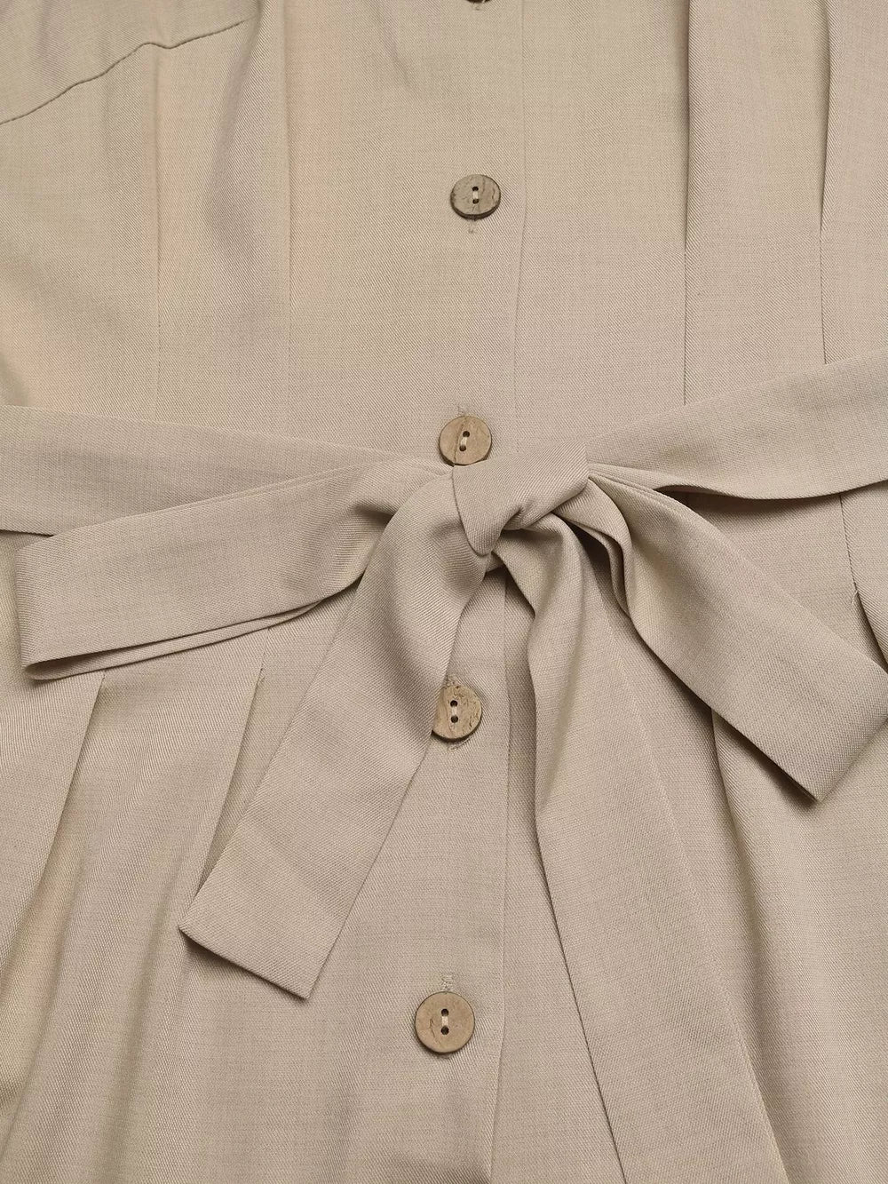 Beige V-neck romper with tie waist and button details