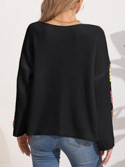 Black knit sweater with colorful granny square sleeves and a boat neck.