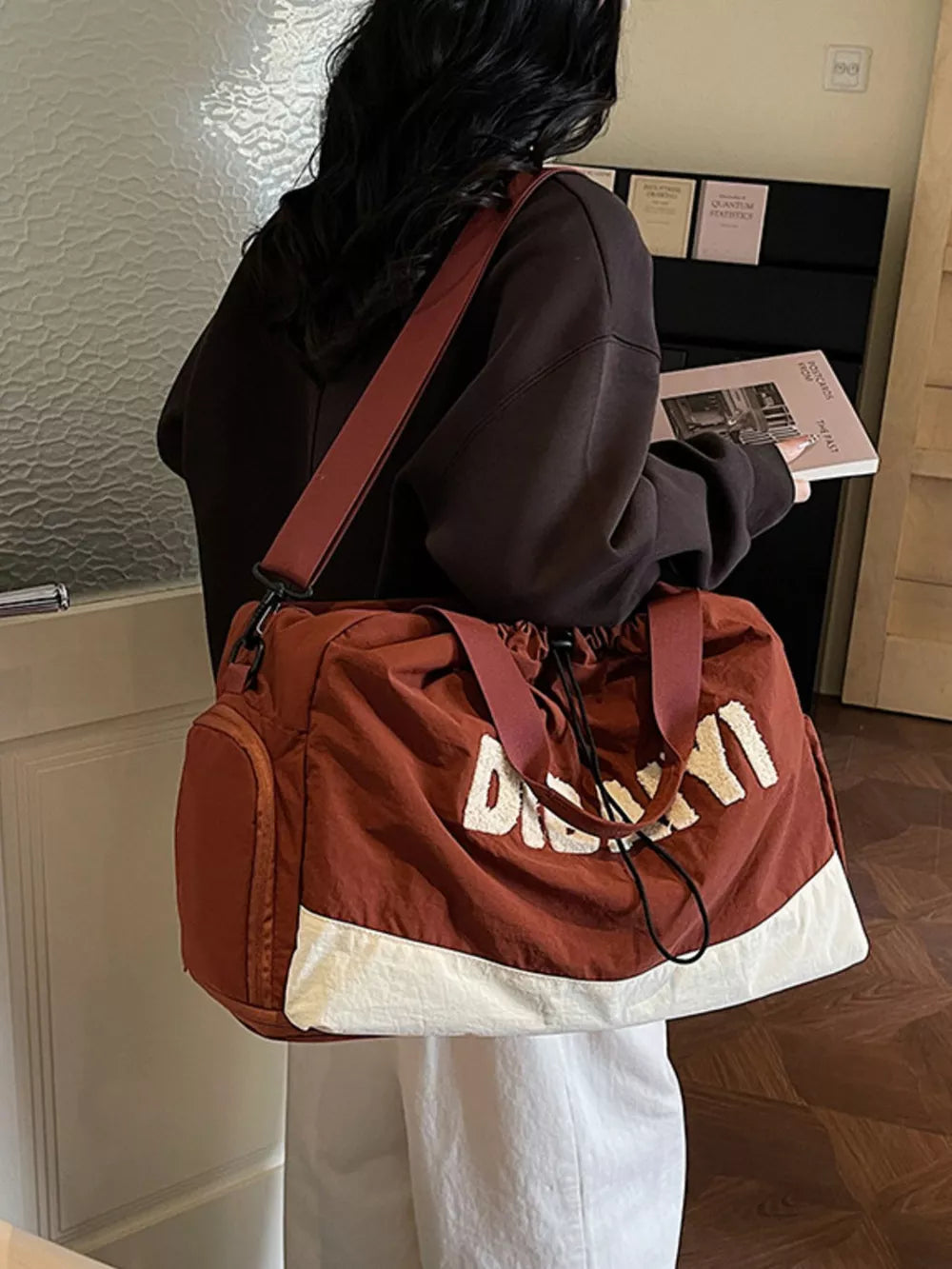 Chic color-blocked travel bag with adjustable strap and white lettering detail.
