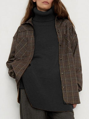 Black ribbed turtleneck sweater with flared sleeves, layered under a plaid shirt jacket.