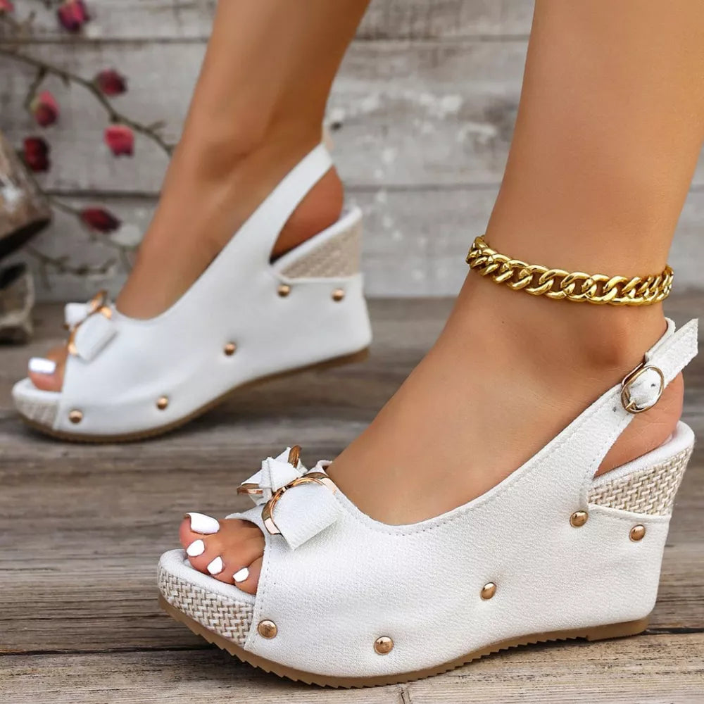 Chic peep toe wedge sandals in white with decorative bow detail and adjustable strap.