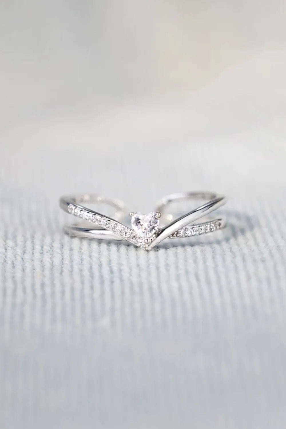 Silver V-shaped ring with diamond accents and a central heart-shaped diamond.