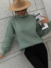 Green ribbed knit turtleneck sweater with voluminous sleeves and V-neck detail.