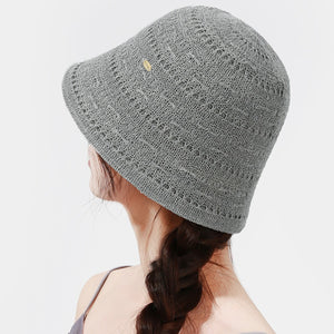 Gray knitted bucket hat with openwork pattern and small gold accent detail.