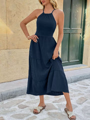 Navy ruched halter midi dress with tiered skirt and tie back detail.
