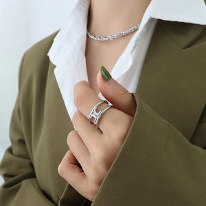 Silver double banded open ring with cut-out detail on a woman's hand.