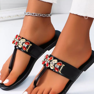 Black jeweled toe-post flat sandals with red and clear crystal floral embellishments.