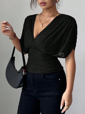 Black surplice dolman sleeve top with ruched waist detail and v-neckline.