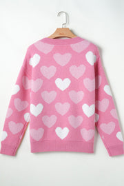 Pink intarsia knit sweater with allover white heart pattern and pearl embellishments.