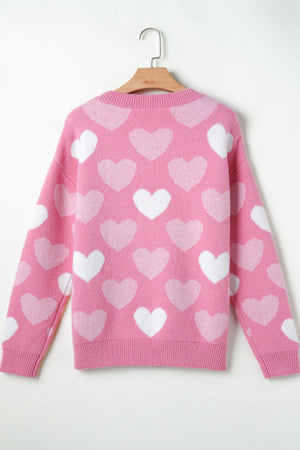 Pink intarsia knit sweater with allover white heart pattern and pearl embellishments.
