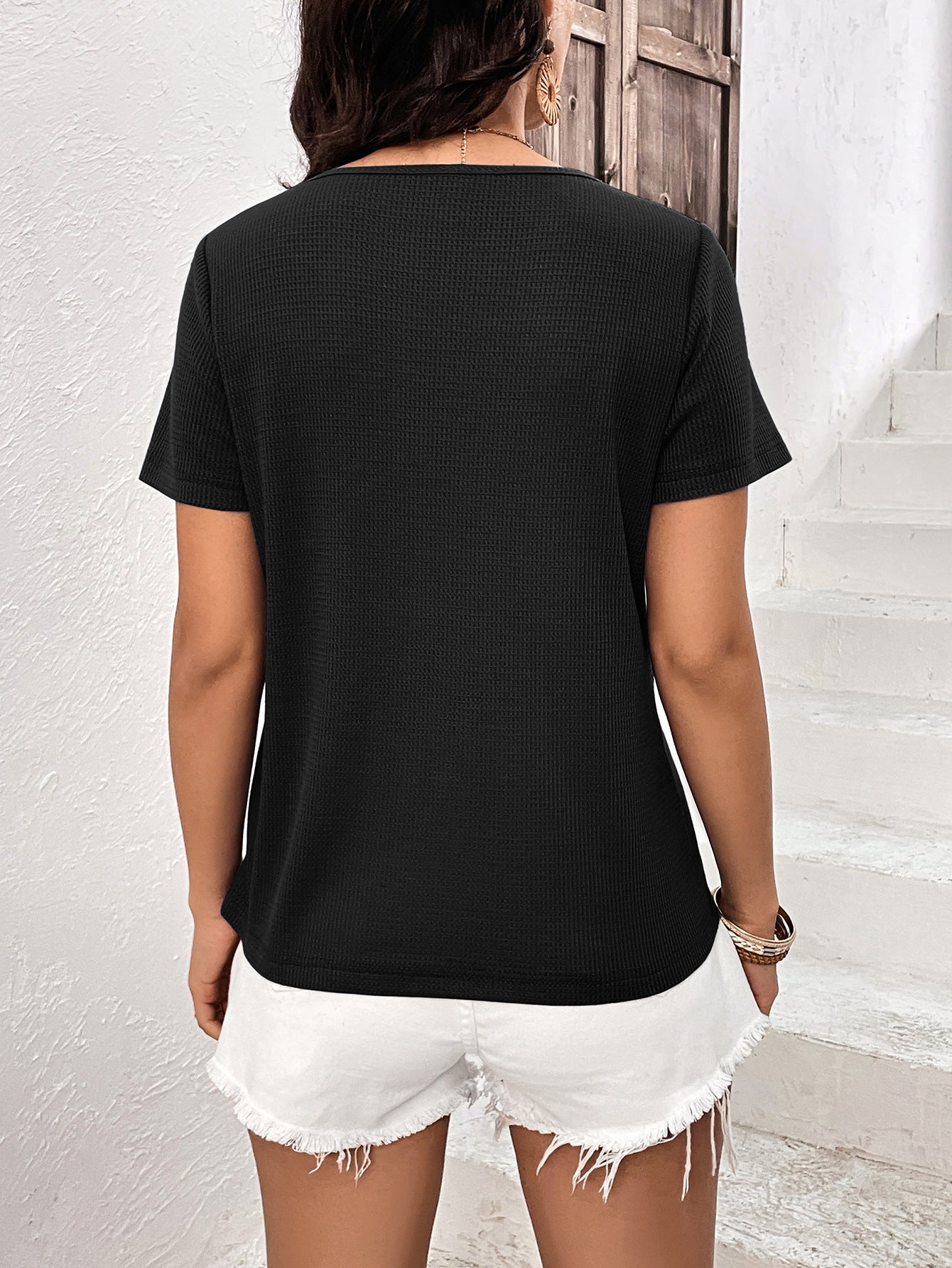 Black waffle knit tee with short sleeves and a crew neck, paired with white denim shorts.