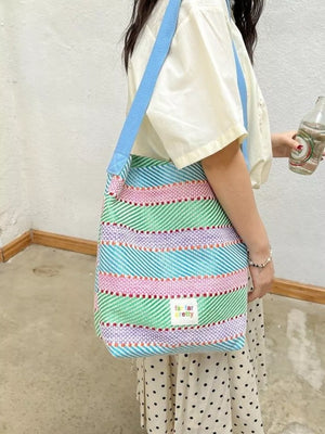 Vibrant striped woven shoulder bag with blue strap and a small "far far pretty" tag.