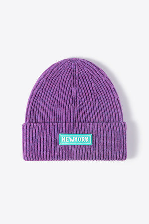 Purple ribbed acrylic beanie with New York patch detail.
