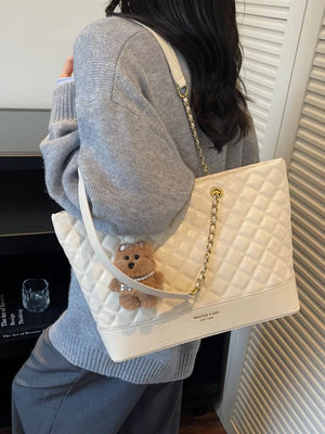 Luxurious quilted ivory shoulder bag with chain strap and teddy bear charm.