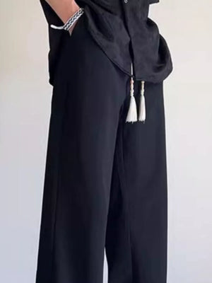 Black men's sweatpants with wide legs and tassel accents on the drawstring.