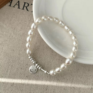 Delicate freshwater pearl bracelet with silver accents and a round charm.