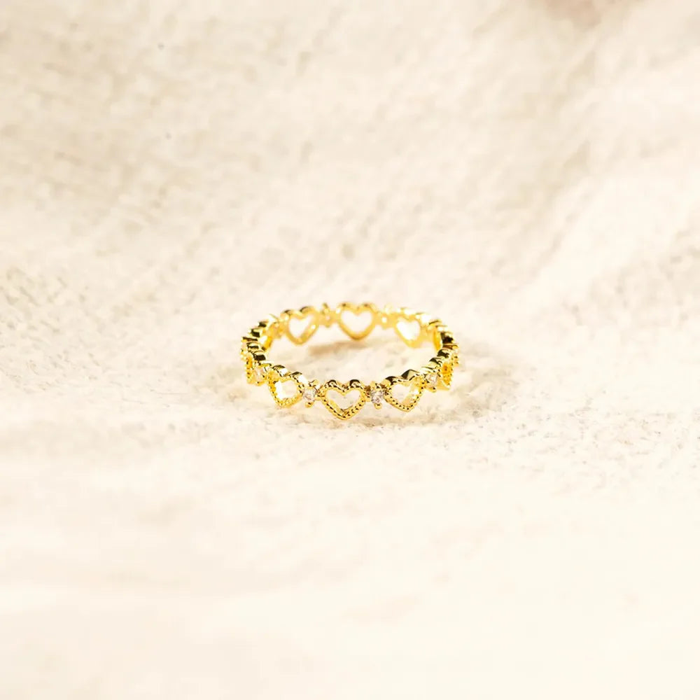 Gold ring with a delicate heart pattern and small clear stones