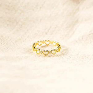 Gold ring with a delicate heart pattern and small clear stones