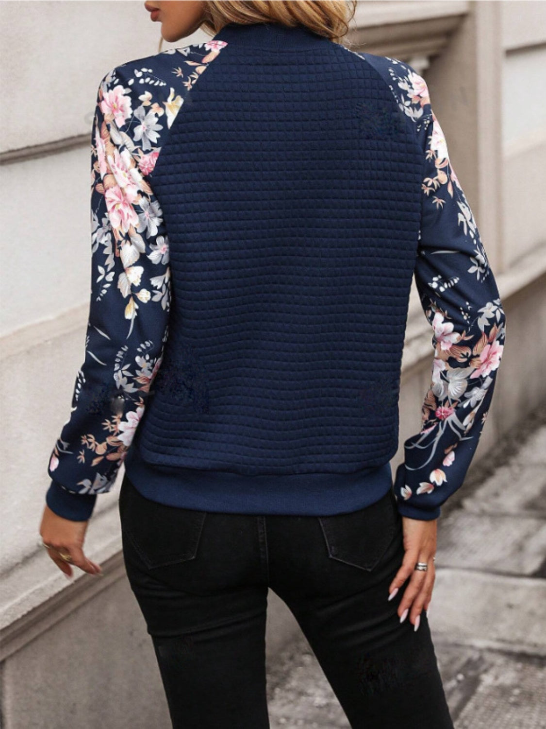 Navy quilted bomber jacket with floral print sleeves and a casual fit.