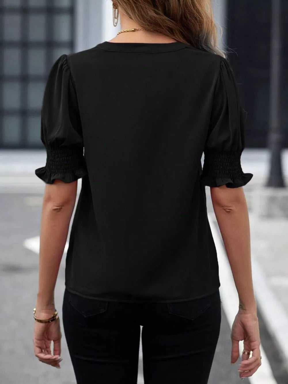 Black blouse with puffed sleeves, smocked cuffs, and a notched neckline.