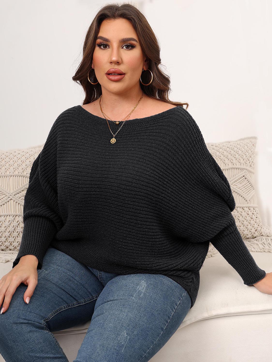 Off-shoulder black ribbed knit sweater with batwing sleeves and a boat neckline.