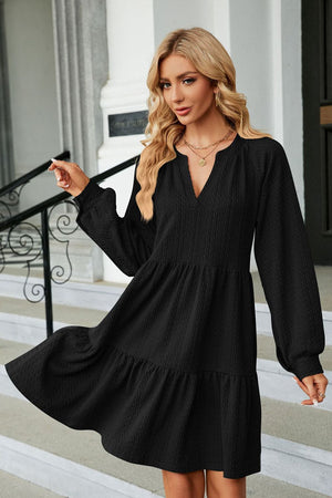 Black textured babydoll mini dress with voluminous sleeves and tiered hem