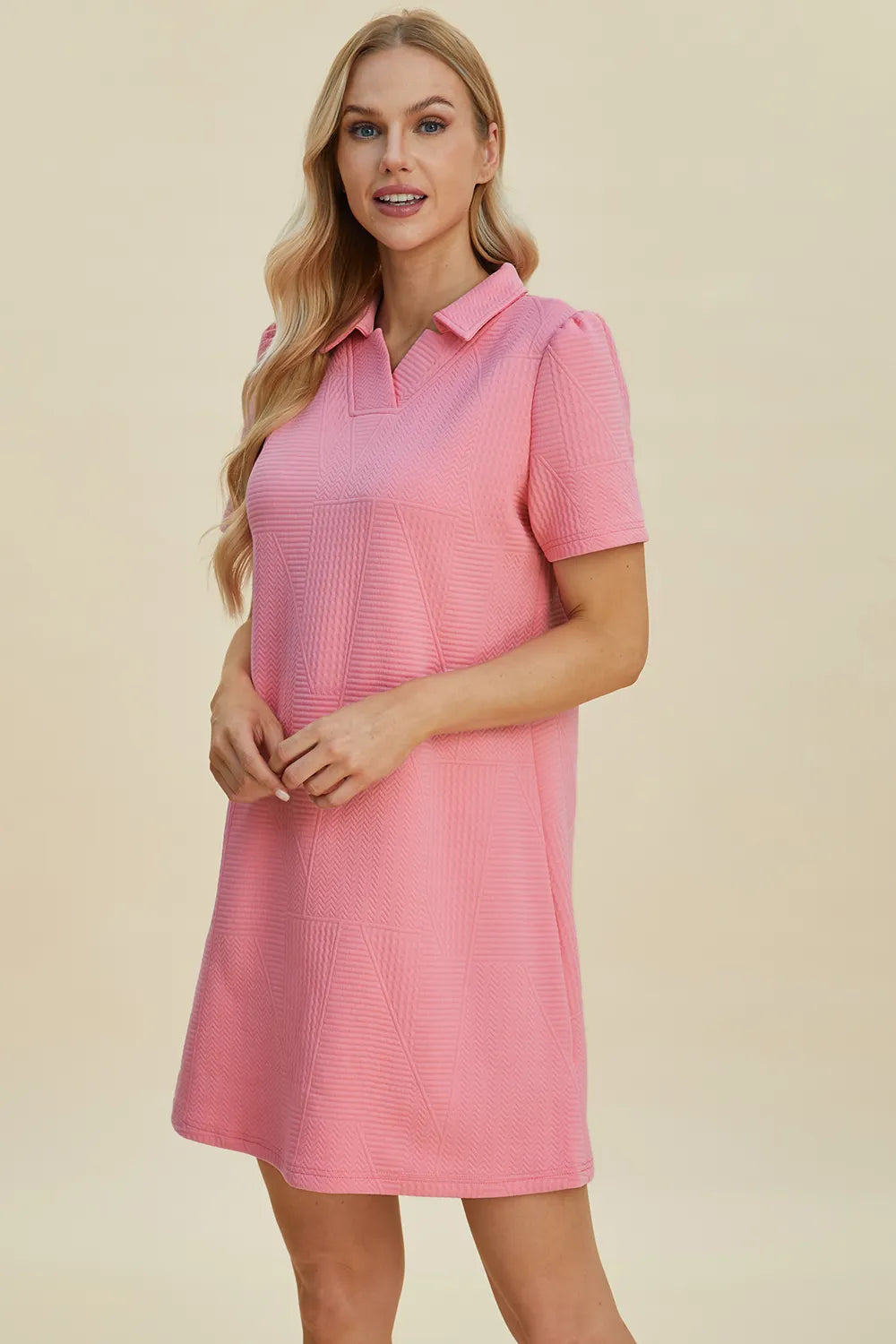 Pink textured V-neck short sleeve mini dress with geometric pattern detail.