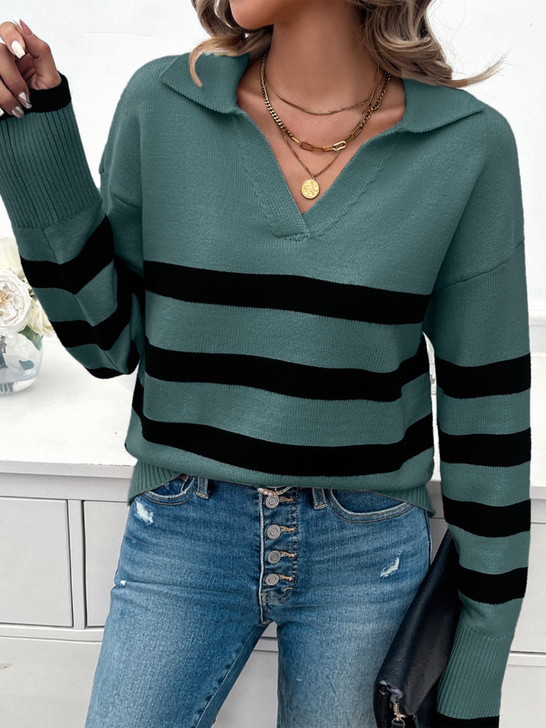 Turquoise knit sweater with black bold stripes, V-neck, and collar.