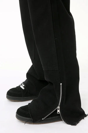 Black bootcut denim pants with zip hem detail and frayed cuffs.