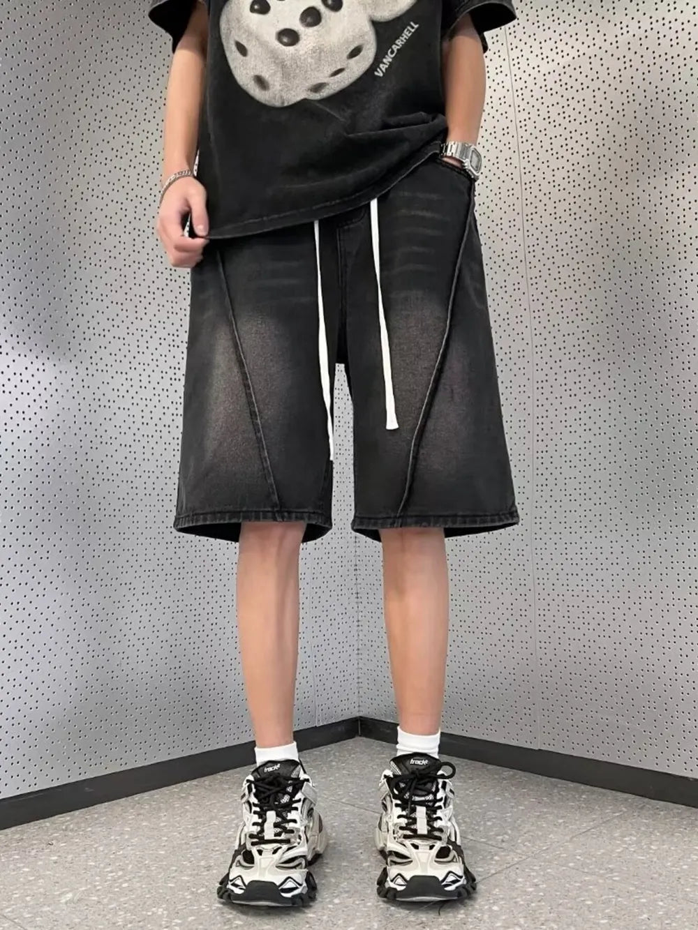Black denim shorts for men with drawstring waist and unique seam detail.