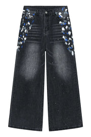 Dark wash denim jeans with painterly blue, white, and grey splatters and a wide flare leg.