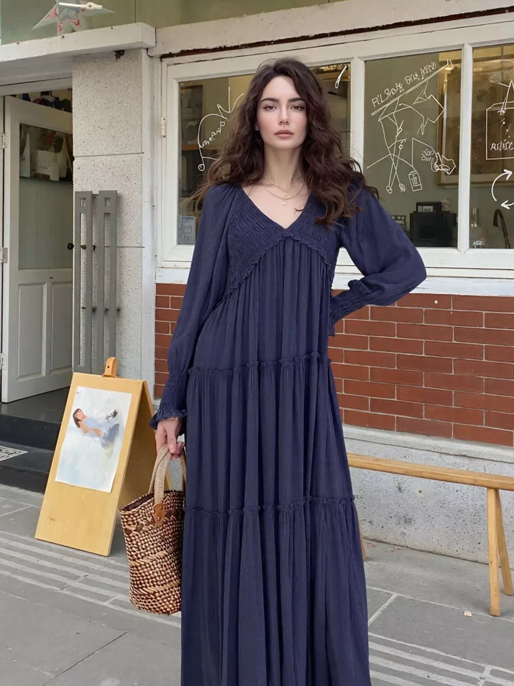 Blue smocked v-neck tiered maxi dress with long sleeves and cinched cuffs.