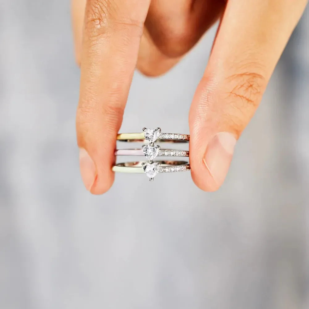 Stack of three sterling silver rings with pave bands and heart-shaped stones in light green, blush pink, and light blue.