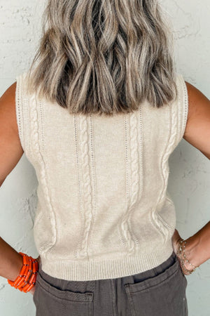 Beige cable knit vest with intricate braided detailing and ribbed trim.