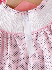 Baby dress with pink polka dots, smocked white yoke, and button front.