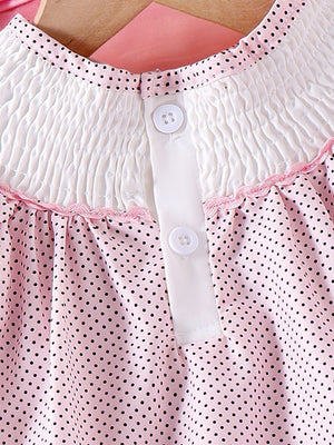 Baby dress with pink polka dots, smocked white yoke, and button front.