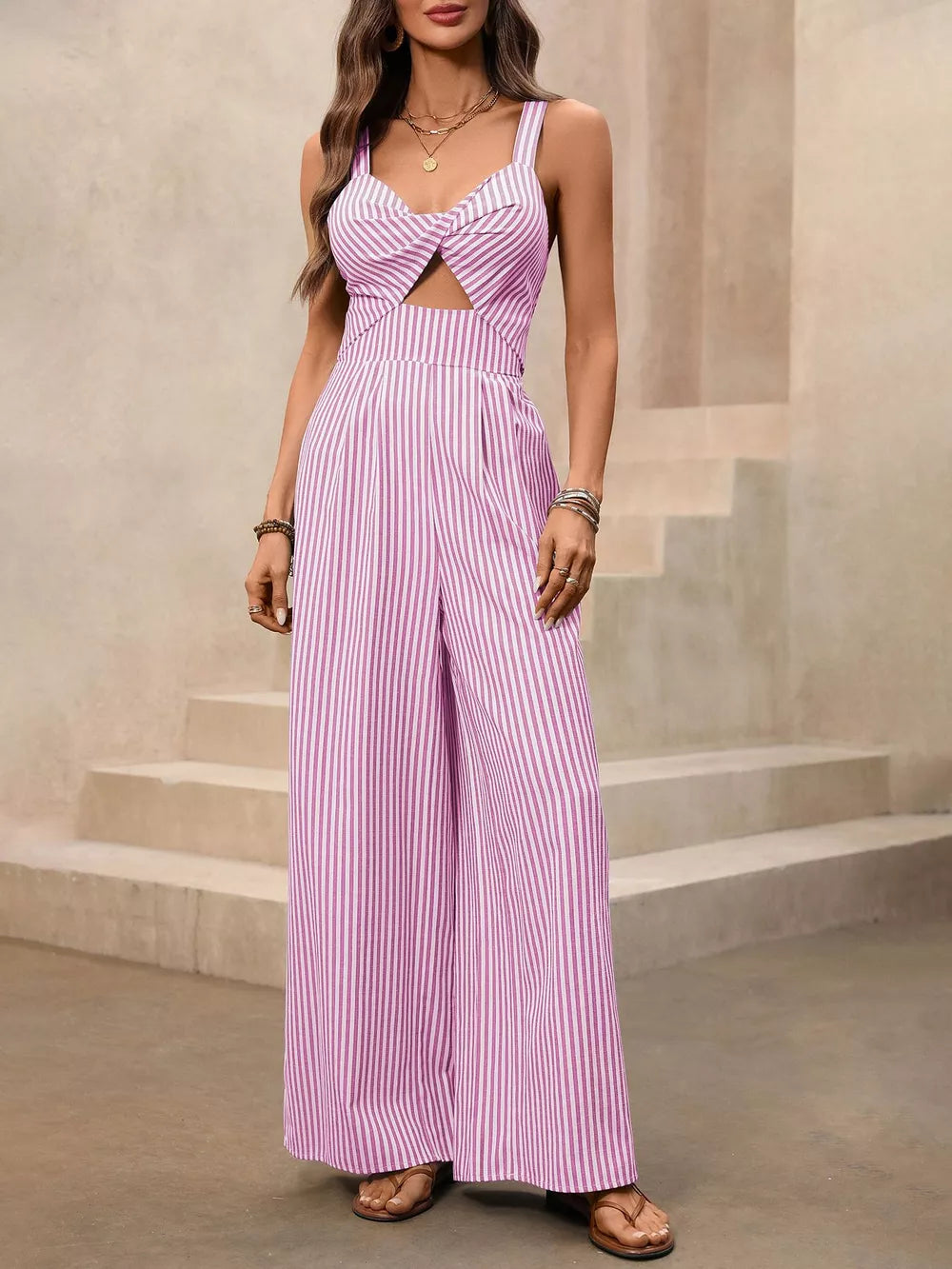 Blush pink striped cotton jumpsuit with twist-front cutout and wide legs.
