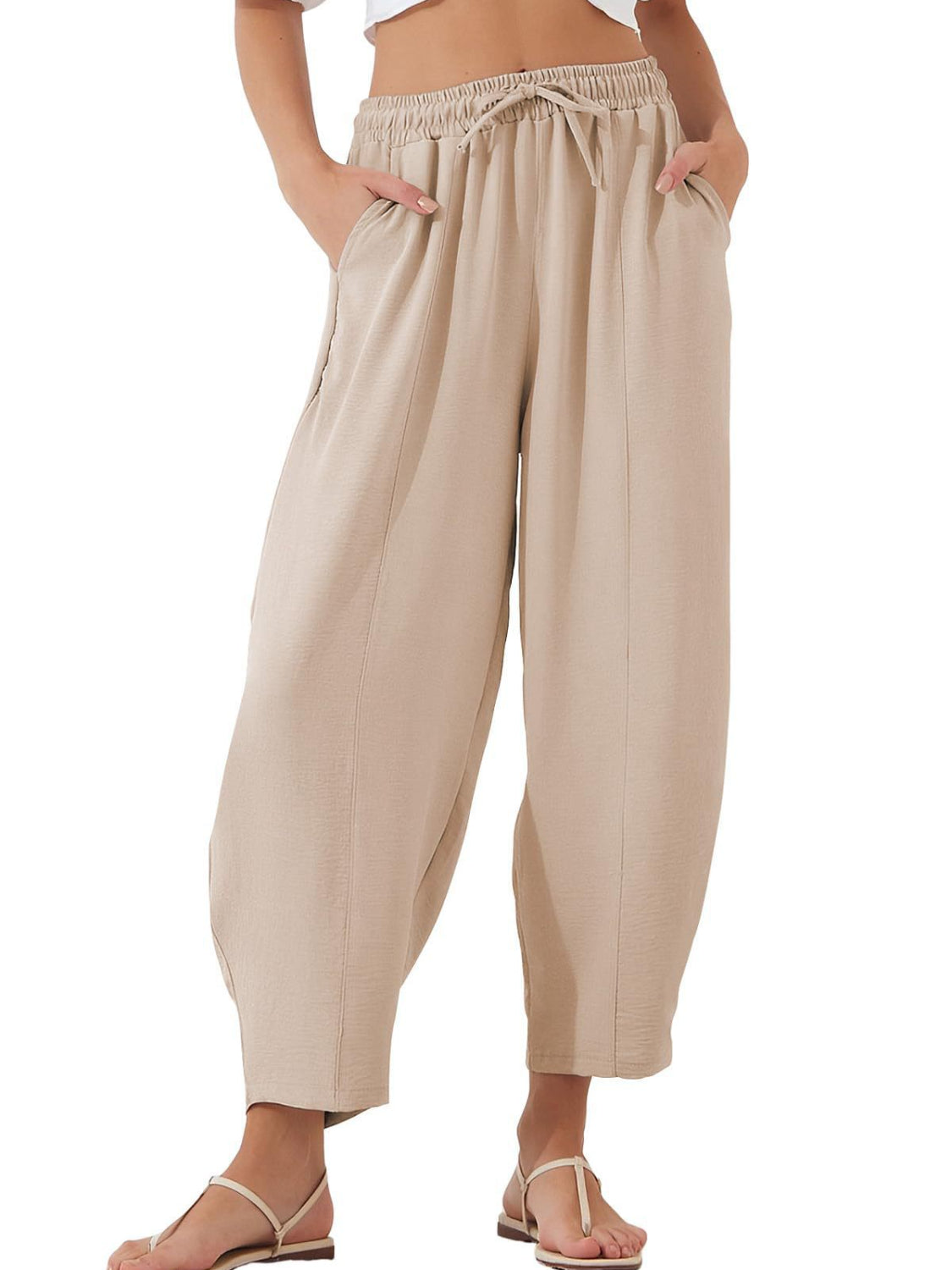 Tan balloon trousers with drawstring waist and sculpted seam detail.