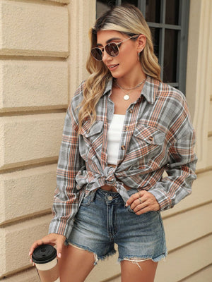 Plaid collared long sleeve shirt with button-down front and chest pockets, styled open over a white crop top.