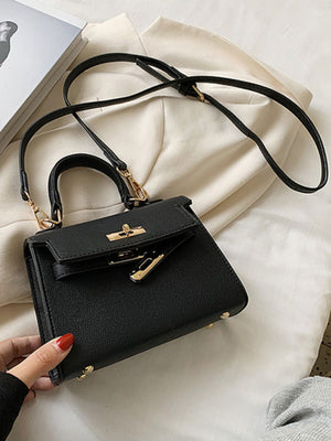 Black mini crossbody bag in faux leather with gold hardware and top handle.