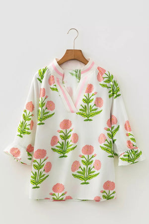 White cotton blouse with pink floral print, notched neckline, and ruffled sleeves.