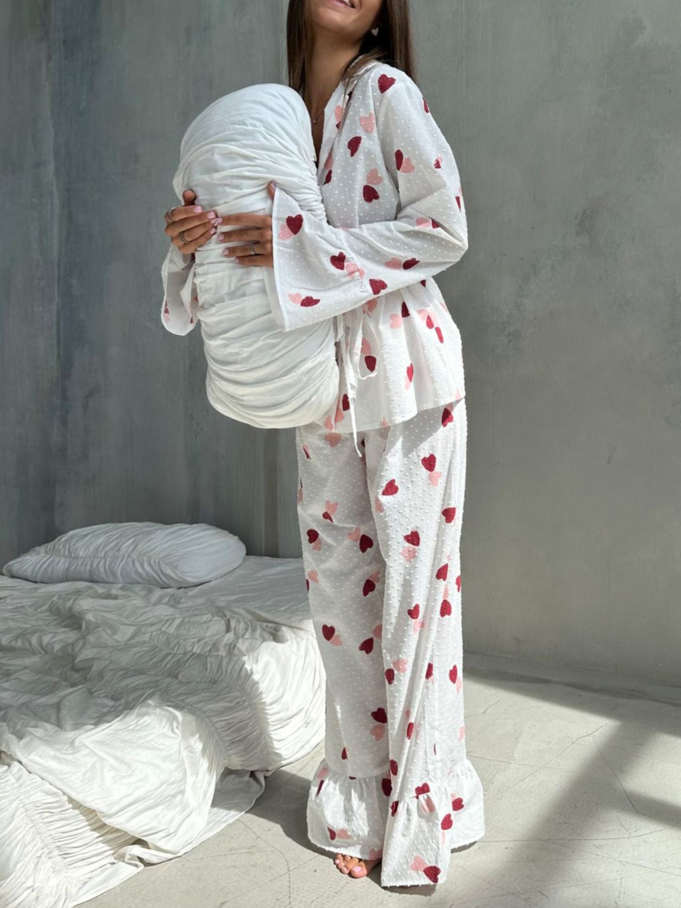 White cotton pajama set with multicolor heart print, collared button-down top and ruffled pants.