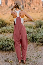 Wide-leg jumpsuit in dusty rose with pockets, V-neck, and adjustable straps.