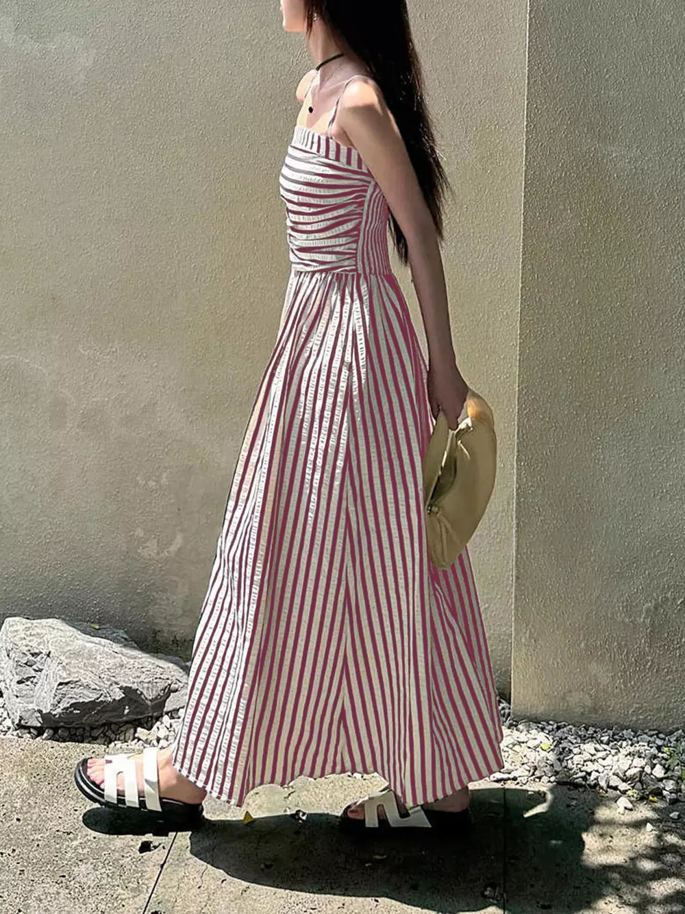 Pink striped maxi dress with slit and spaghetti straps, worn with white sandals.
