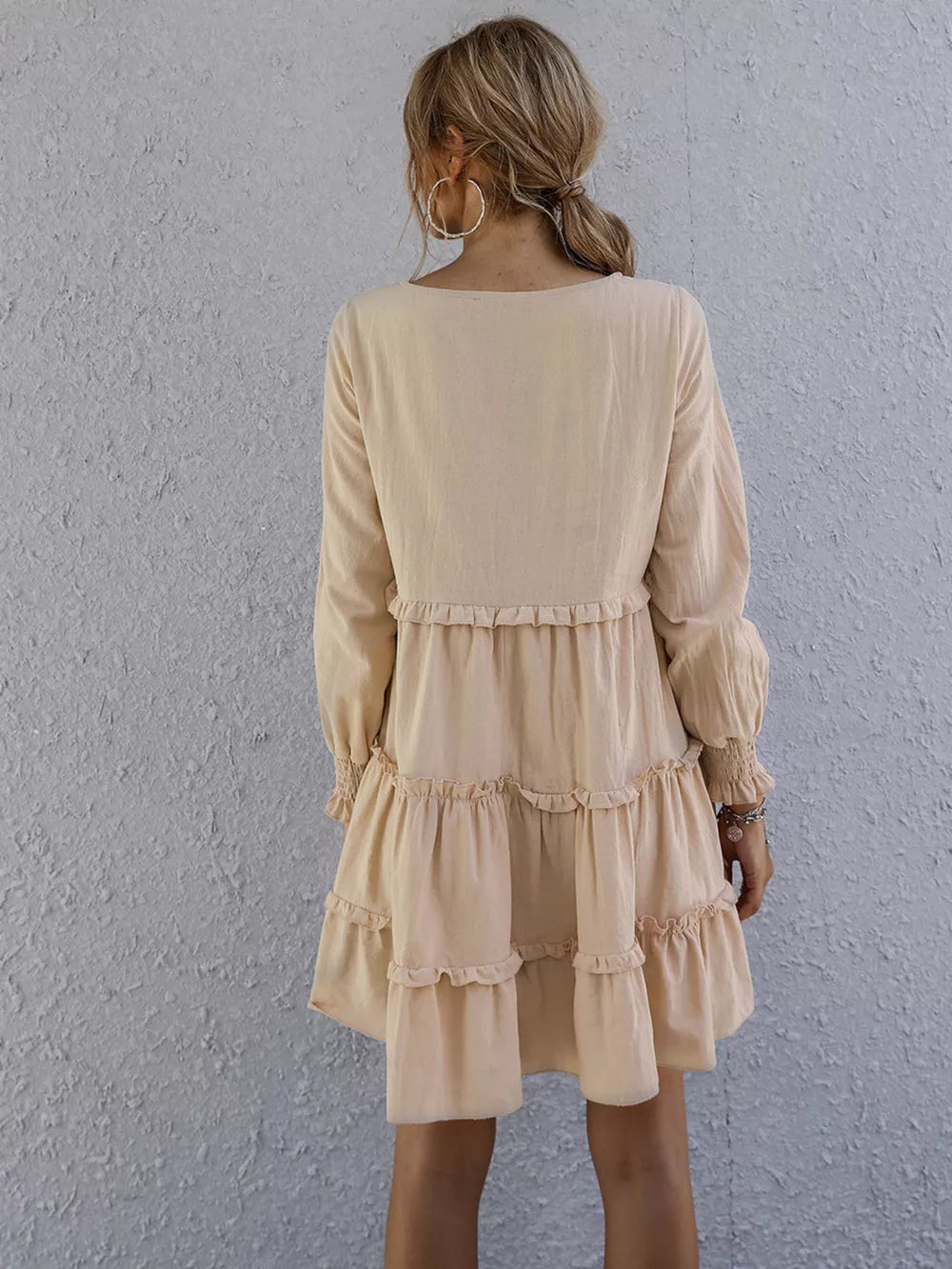 Apricot ruffled mini dress with long sleeves and tiered skirt.